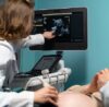 Gynecologist performing abdominal ultrasound scan on a female patient during a routine health checkup.